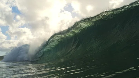 Green Ocean Wave Rising Over Rippling Water Beneath Sunlit Clouds Stock Footage 344382392