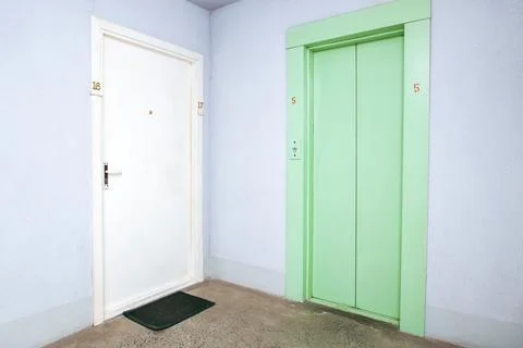 Green old elevator in hallway and door to apartment Stock Photos