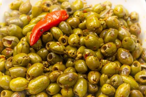 Green olive salad background with a chilli on top Foto stock