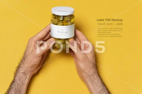Green olives conserve glassy jar with round cap on hands mock-up series PSD Template