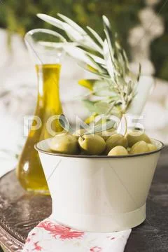 Green olives, olive sprig & olive oil on table out of doors Stock Photos
