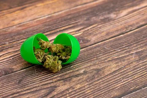 A Green Open Easter Egg With Cannabis Coming Out of It Stock Photos