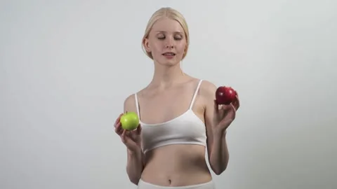 Green or red apple. A slender blonde woman dances vigorously with apples in her Stock Footage 157680013