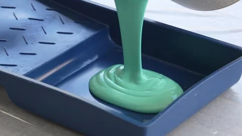 Green paint is poured into the roller tray. Stock Footage 252736083
