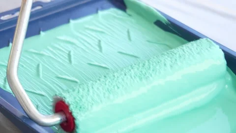Green paint is poured into the roller tray. Stock Footage 253521502