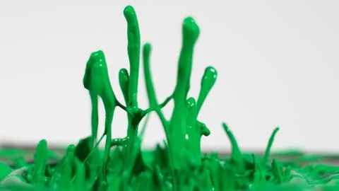Green paint splattering up from surface Stock Photos