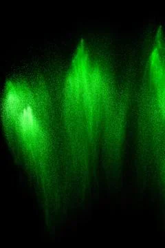 Green particles explosion on black background. Color dust splash. Stock Photos