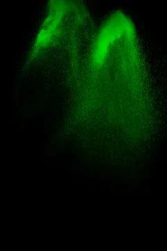 Green particles explosion on black background. Color dust splash. Stock Photos