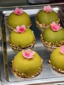Green pastries with a rounded hemisphere shape are topped with a pink flowe.. Stock Photos