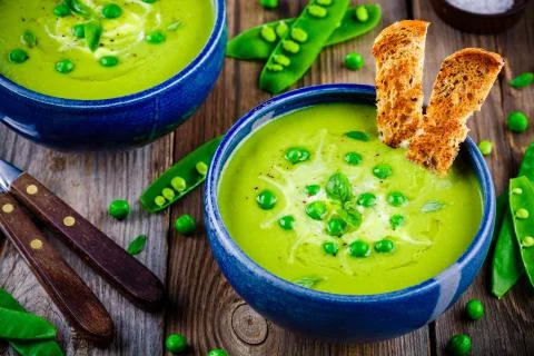 Green pea soup on wooden rustic background Stock Photos