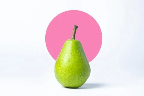 Green pear on a creative background. Pear on the background of a lilac circle. Stock Photos