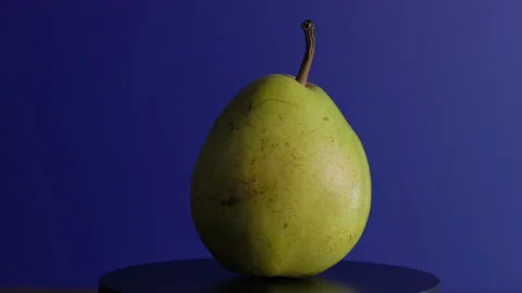 Green pear rotates on a blue background Stock Footage 330687236