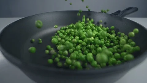 Green peas are throwed to the pan in slow motion, fresh vegetables are falling Stock Footage 120011710