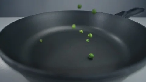 Green peas fall in slow motion to the pan, fresh vegetables are falling in 240 Stock Footage 120058654