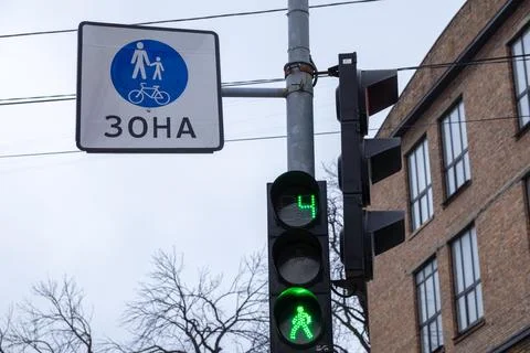 A green pedestrian traffic light with a countdown timer next to a sign desi.. Stock Photos