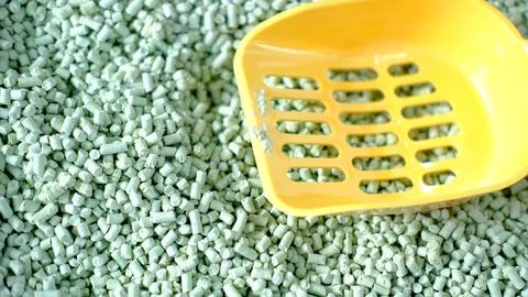 Green pellets scattered on a surface with a yellow scoop resting atop 写真素材