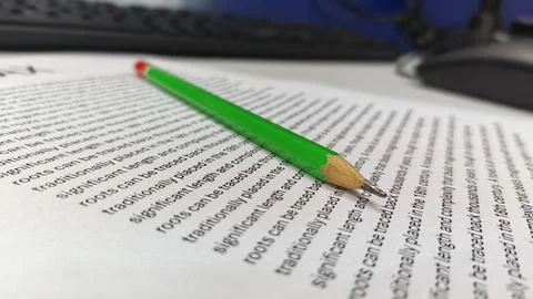 Green Pencil Resting on Text Document on Office Desk Stock Photos
