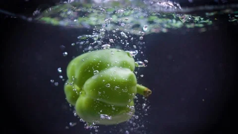 Green pepper falls into the water. Video stock 122979611