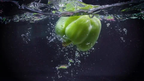 Green pepper falls into the water. Video stock 122979698