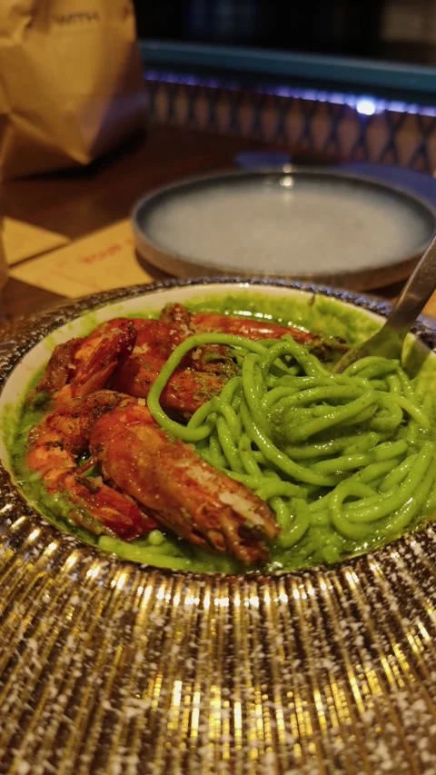 Green pesto spaghetti plated with grilled jumbo shrimp, vibrant seafood pasta Stock Footage 344911152