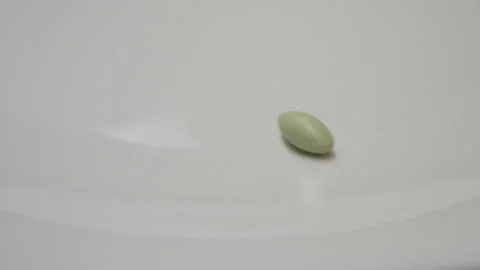 Green pill rotate, close up A single green pill laid out on a white surface Stock Footage 86172708