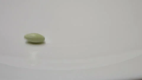 Green pill rotate, close up A single green pill laid out on a white surface Stock Footage 86172709