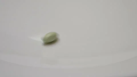 Green pill rotate, close up A single green pill laid out on a white surface Stock Footage 86177337
