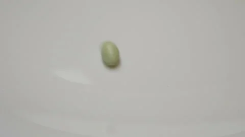 Green pill rotate, close up A single green pill laid out on a white surface Stock Footage 86177382