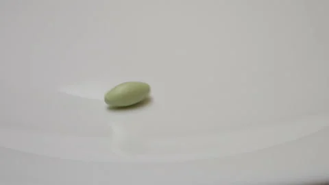 Green pill rotate, close up A single green pill laid out on a white surface Stock Footage 86178419