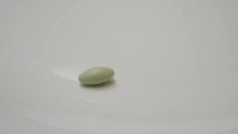 Green pill rotate, close up A single green pill laid out on a white surface Stock Footage 86178438