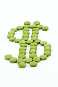 Green pills arranged in a dollar sign shape Stock Photos