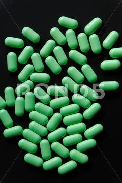 Green pills spill on black background top view Stock Photos