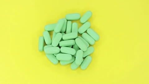 Green pills on a yellow background Stock Footage 170022500