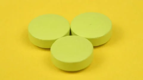 Green pills on yellow background. Side view. Loop motion. Stock Footage 167060391