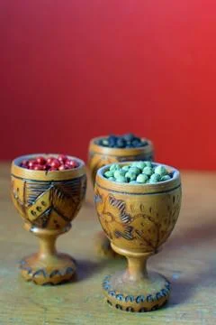 Green, pink and black peppercorns in wooden glass. Stock Photos