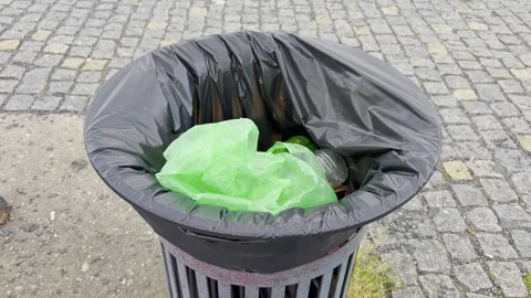 A green plastic bag lies inside a street trash bin with a black liner The c.. Stock Footage 340648801