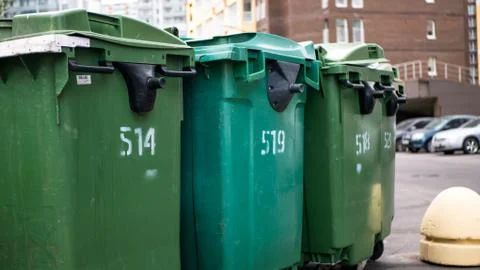 Green plastic garbage collection containers. In a row on the street Stock Photos