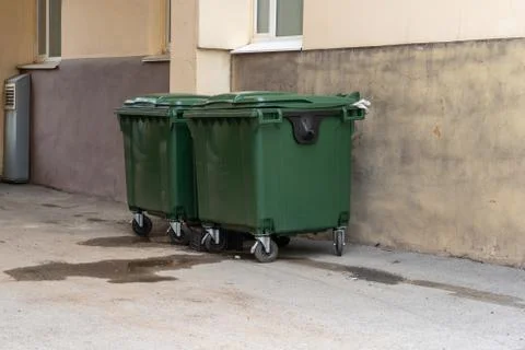 Green plastic garbage containers installed along in the yard of the house. Th Stock Photos