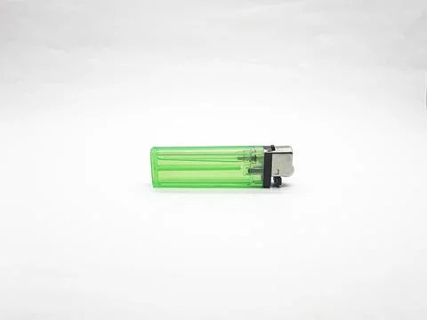Green plastic lighter on a white surface for smoking or starting fire Stock Photos