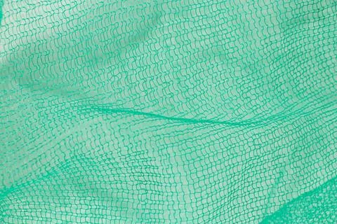 Green plastic mesh close-up, texture of packaging mesh for vegetables Stock Photos
