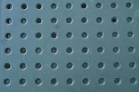 Green plastic surface with a grid of circular holes arranged in rows Stock Photos