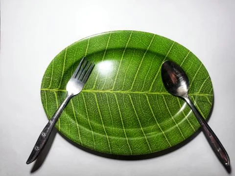 Green plate leaf theme isolated white background with spoon and fork Fotos Stock