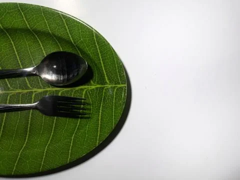 Green plate leaf theme isolated white background with spoon and fork Stockfoto's