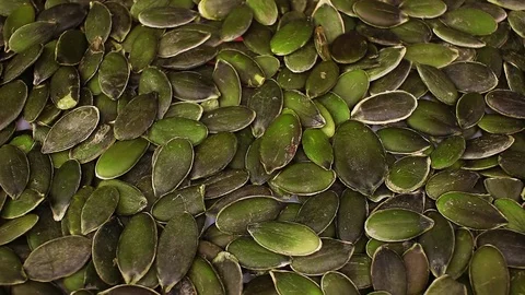 Green pumpkin seeds closeup texture video on rolling rotating looping plate Stock Footage 104327086