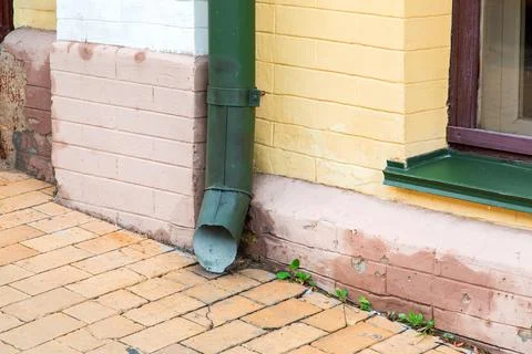 Green rain pipe rain system on the facade of the brick house. Stock Photos