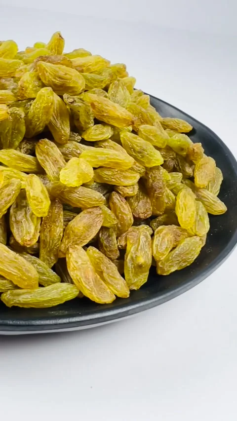 Green raisins in dark plate, white background, vertical, low angle Stock Footage 336847784