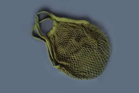 A green reusable string bag for different products on the grey background. Stock Photos