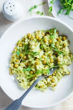 Green risotto with broccoli, green peas and sprouts in white plate, top view. Foto stock