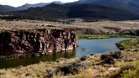 The Green River passes reddish cliffs in Browns Park National Wildlife Refuge Stock Footage 107488069