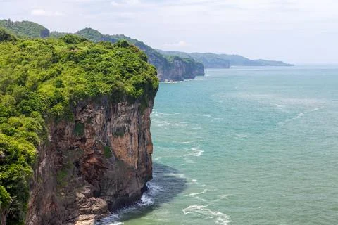 Green rocky coast of Java island on sunny day in Indonesia. Fotos de archivo